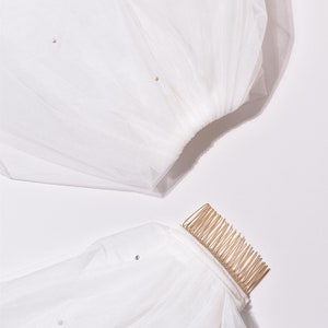May include: White tulle bridal veil with a gold comb and pearl embellishments.