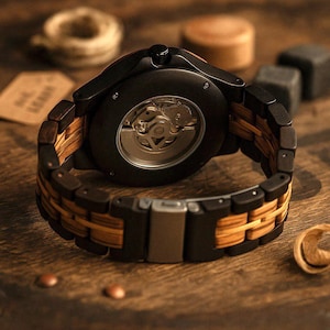 May include: A wristwatch featuring a black circular case with an exposed mechanical movement on the back. The band is constructed from alternating links of dark black wood and light tan wood, secured by a metallic silver-toned folding clasp.