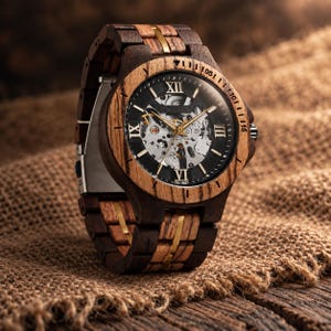 Könnte beinhalten: Eine Armbanduhr mit einem Gehäuse und Gliederarmband aus hell- und dunkelbraunem Holz mit goldfarbenen Metallakzenten. Das runde Zifferblatt zeigt ein skelettiertes mechanisches Uhrwerk, goldfarbene Zeiger und schwarze römische Ziffern.