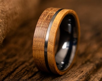 May include: A ring featuring a wide band constructed from two distinct shades of light and medium brown wood, separated by a thin, vertical dark grey metal inlay. The interior of the ring is finished in a smooth, polished dark grey metal surface.