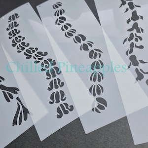 May include: Several white plastic stencils with black floral designs. The stencils feature various repeating patterns of stylized flowers and leaves. The text "Chill Pineapples" is visible in the image.