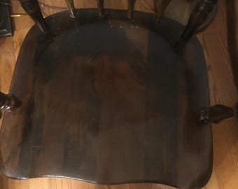 May include: A dark brown wooden chair with a curved back and spindle legs. The chair is made of solid wood and has a natural finish.