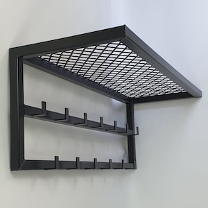 May include: Black metal wall-mounted shelf with a wire mesh top and two rows of hooks.
