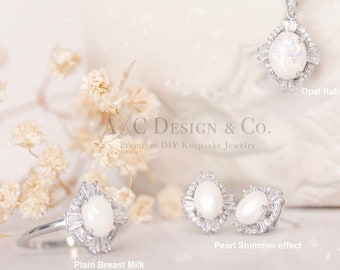 May include: A set of silver jewelry featuring a necklace, ring, and earrings. The necklace has a large oval pendant with a white opal-like stone surrounded by smaller stones. The ring and earrings have similar oval stones with a pearl-like shimmer. The text "AXC DESIGN & CO. Premium DIY Keepsake Jewelry" is visible in the image.