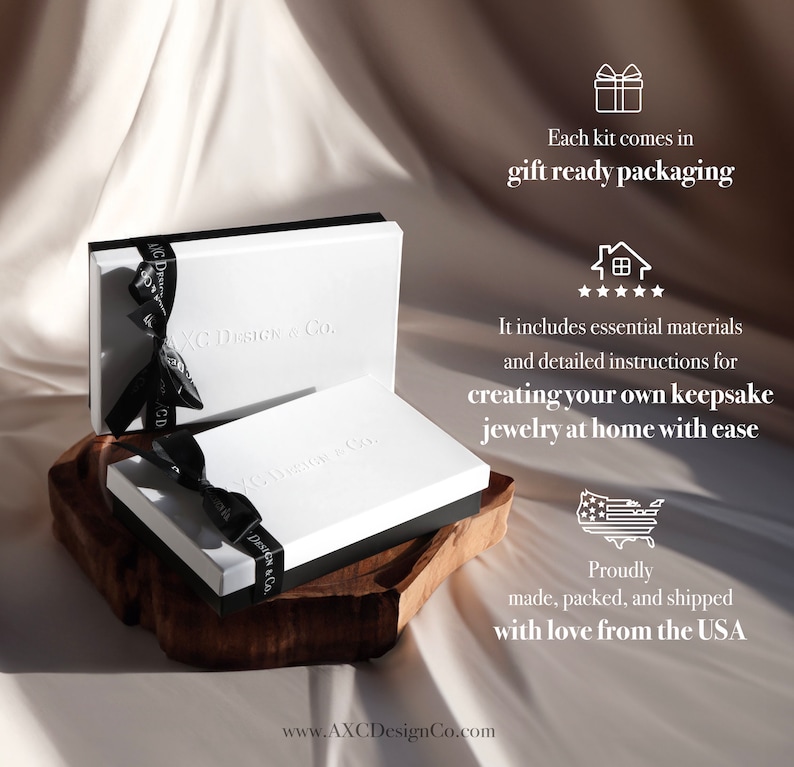 May include: Two white boxes with black trim, tied with black ribbons, are displayed on a wooden surface. The boxes are embossed with "AXC Design & Co." and the text "Each kit comes in gift ready packaging" is visible. The image suggests a jewelry-making kit.