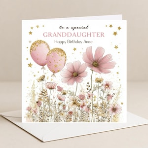 May include: A birthday card with the message "to a special GRANDDAUGHTER Happy Birthday Anne". The design includes pink balloons with gold glitter, pink cosmos flowers, and gold stars on a white background. The card is presented in a white envelope.
