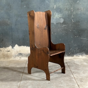 May include: A wooden chair with a high back and a simple design. The chair is made of dark brown wood and has a slightly distressed finish.