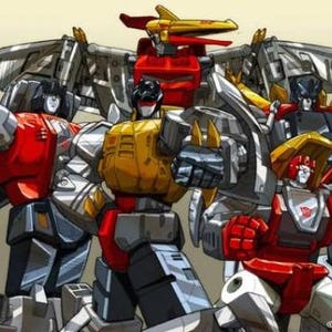 May include: A group of five red, yellow, and gray robot toys with wings and weapons. The robots are posed in a fighting stance. The image includes the text "Hasbro 2002".