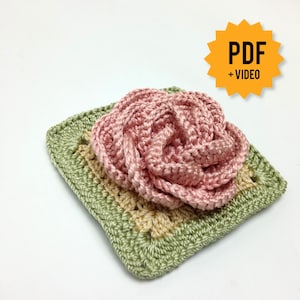 Peut inclure: Un carré crocheté avec une rose rose au centre. Le carré est vert et beige. L'image comprend le texte "PDF + VIDEO".