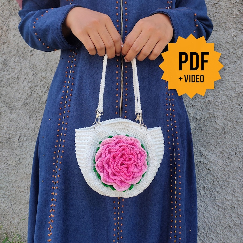 Pode incluir: Bolsa de croch&ecirc; branca com um design de rosa rosa. A bolsa tem uma al&ccedil;a branca e um forro branco. PDF + VIDEO.