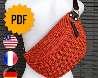 May include: A burnt orange crochet fanny pack featuring a textured bobble stitch pattern, a matching orange zipper closure, and a black strap attached with gold-tone metal hardware. The bag is displayed on a white mannequin torso.