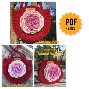 Pode incluir: Uma bolsa de croch&ecirc; com um grande desenho de flor de rosa em tons de rosa e vermelho. A bolsa tem uma al&ccedil;a vermelha e uma pequena etiqueta marrom que diz "Ew Craft". A imagem inclui o texto "My Blooming Rose Pattern By Tutorial Rajutad" e "PDF + VIDEO".
