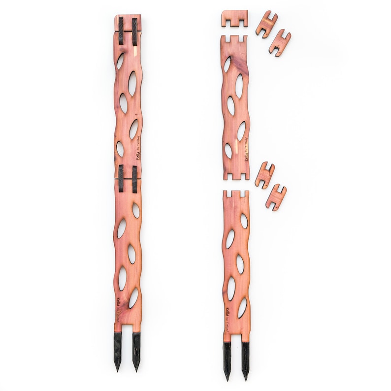 May include: Two wooden garden stakes with a natural finish, featuring an open, oval design. The stakes have black pointed ends for easy ground insertion. Additional wooden connectors are also shown, suggesting an assembly process. The stakes are labeled with the text "Etta by Tricia".