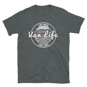 May include: A dark heather grey t-shirt with a white circle graphic. The graphic features a road leading through a mountain pass with the text "Live Wild Van Life Live Free".