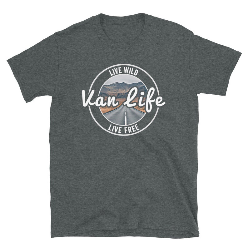 May include: A dark heather grey t-shirt with a white circle graphic. The graphic features a road leading through a mountain pass with the text "Live Wild Van Life Live Free".