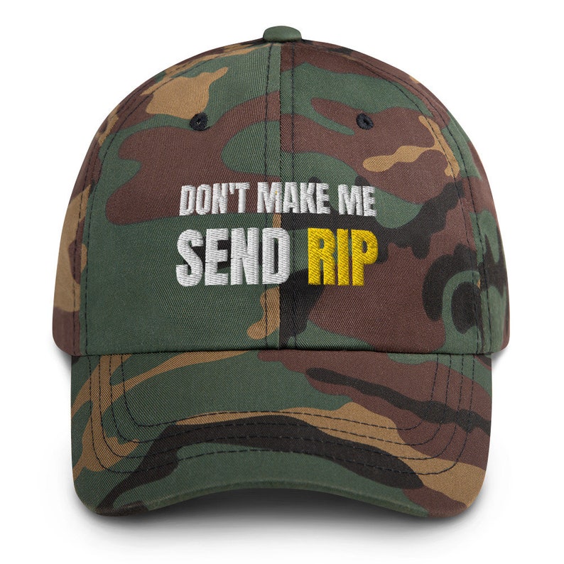 Puede incluir: Una gorra de b&eacute;isbol de camuflaje con el texto "DON'T MAKE ME SEND RIP" bordado en blanco y amarillo.