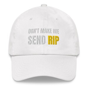 Puede incluir: Gorra de b&eacute;isbol blanca con el texto "Don't Make Me Send Rip" bordado en plata y oro.