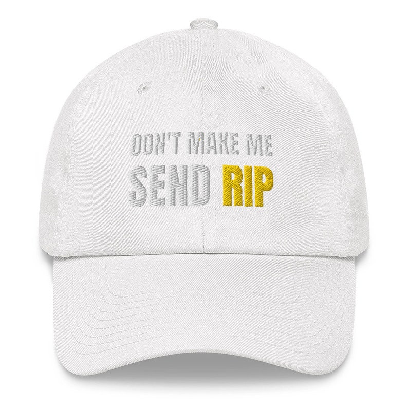 Puede incluir: Gorra de b&eacute;isbol blanca con el texto "Don't Make Me Send Rip" bordado en plata y oro.