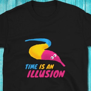 May include: Black t-shirt featuring a worm-like figure in blue, yellow, and pink colours. The worm has two eyes and the text "TIME IS AN ILLUSION" is printed below it.