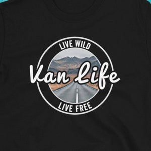 May include: Black t-shirt with a white circle graphic that says "Live Wild Van Life Live Free" with a picture of a road through a mountain landscape.