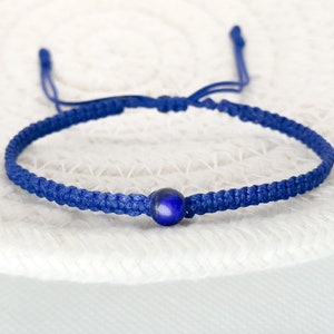May include: A blue braided bracelet with a single dark blue gemstone bead.