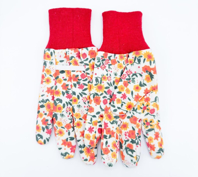 May include: A pair of gardening gloves with a white background. The gloves have a red cuff and a floral pattern of orange, yellow, and red flowers on a white background. The gloves are designed for gardening.
