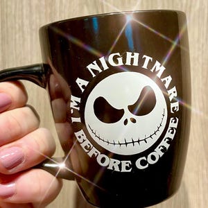 Puede incluir: Taza de cer&aacute;mica negra con el texto "I'm a Nightmare Before Coffee" en un dise&ntilde;o circular. El dise&ntilde;o presenta una cara blanca de Jack Skellington. La taza tiene un asa negra.