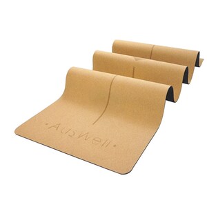 May include: A rolled up cork yoga mat with a black edge and the text "AusWell." printed on the mat.