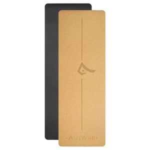 May include: A cork yoga mat with a black yoga mat underneath. The cork mat is brown and has a subtle texture. The mat has a logo that says "AusWell" in gold.
