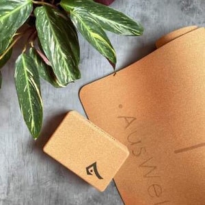 May include: A cork yoga mat and a cork yoga block with the word "Auswell" printed on the mat.