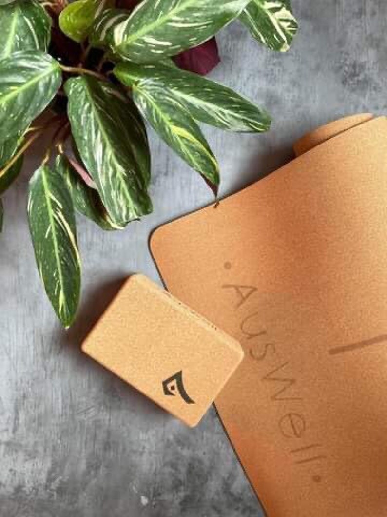 May include: A cork yoga mat and a cork yoga block with the word "Auswell" printed on the mat.