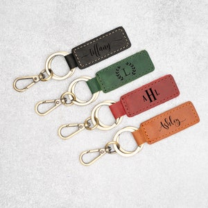 Puede incluir: Cuatro llaveros de cuero con anillas doradas. Los llaveros están personalizados con nombres e iniciales. Los llaveros son marrones, verdes, rojos y negros.