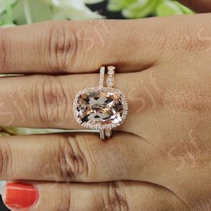 May include: A rose gold engagement ring set with a large, cushion-cut morganite center stone surrounded by smaller diamonds. The band is also set with diamonds.