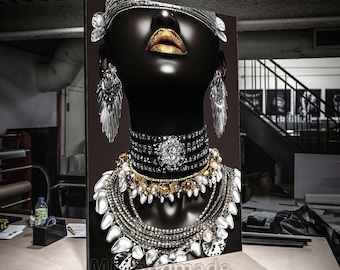 May include: A black and white portrait of a woman wearing a silver headpiece and multiple necklaces with gold and silver accents. The woman's eyes are closed and her lips are painted gold.