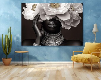 May include: A black and white portrait of a person with white flowers covering their eyes. The person is wearing a silver necklace and a silver bracelet. The background is a dark brown.