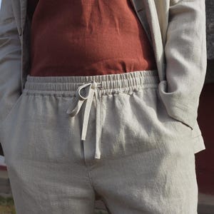 May include: A pair of light gray linen pants with a drawstring waist. The pants have a relaxed fit and are made of a lightweight, breathable fabric.