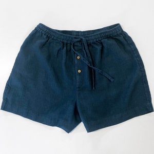 May include: Dark blue linen shorts with a drawstring waist and button closure.