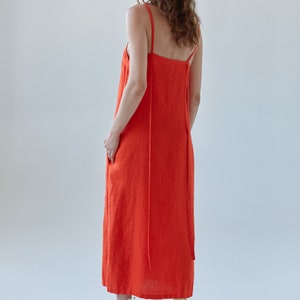 May include: A bright orange maxi dress with thin straps. The dress is made of a lightweight fabric and has a relaxed fit.