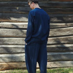 May include: A person wearing a dark blue long-sleeved shirt and matching pants. The shirt has a button-up collar and the pants have a loose fit.