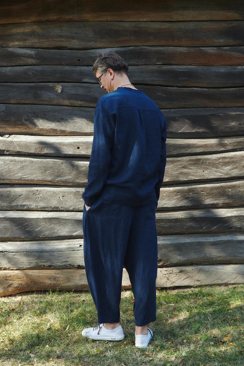 May include: A person wearing a dark blue long-sleeved shirt and matching pants. The shirt has a button-up collar and the pants have a loose fit.