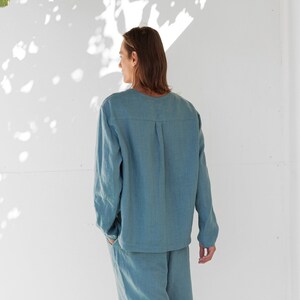 May include: A light blue linen shirt and pants set. The shirt has a long sleeve and a relaxed fit. The pants have a straight leg.