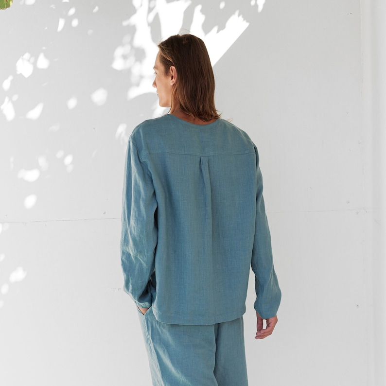 May include: A light blue linen shirt and pants set. The shirt has a long sleeve and a relaxed fit. The pants have a straight leg.