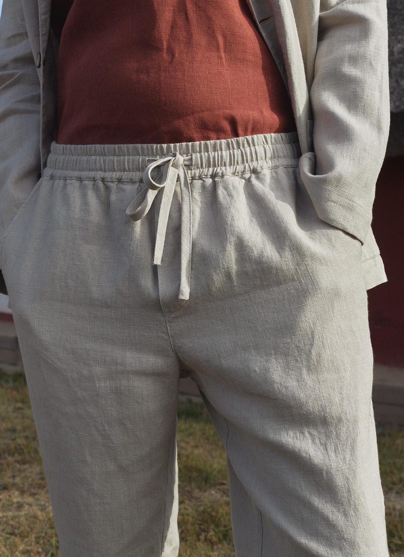 May include: A pair of light gray linen pants with a drawstring waist. The pants have a relaxed fit and are made of a lightweight, breathable fabric.