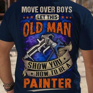 Könnte beinhalten: Marineblaues T-Shirt mit dem Text "MOVE OVER BOYS LET THIS OLD MAN SHOW YOU HOW TO BE A PAINTER". Das Design zeigt eine Farbspritzpistole und ein Banner mit Sternen.