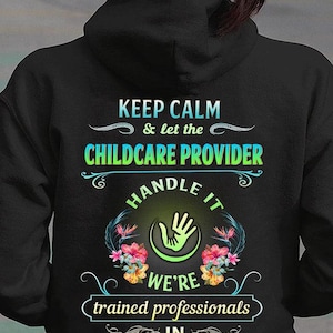 Könnte beinhalten: Schwarzer Kapuzenpullover mit dem Text "KEEP CALM & let the CHILDCARE PROVIDER HANDLE IT WE'RE trained professionals IN DEALING WITH CRAZY". Das Design beinhaltet eine Handgrafik und florale Akzente.