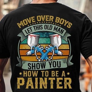 Könnte beinhalten: Schwarzes T-Shirt mit einer Grafik, die zwei gekreuzte blaue und weiße Farbspritzgeräte zeigt. Der Text lautet "MOVE OVER BOYS LET THIS OLD MAN SHOW YOU HOW TO BE A PAINTER" in gold- und weißfarbenen Buchstaben.