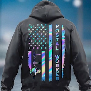 May include: Black hooded sweatshirt featuring a holographic American flag design with stars and stripes. The words "POSTAL WORKER" are printed vertically on the right side. A mailbox and heartbeat graphic are also included.