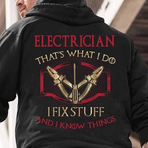 May include: Black hooded sweatshirt with a gold and red graphic design. The text on the graphic reads "Electrician That's What I Do I Fix Stuff And I Know Things".
