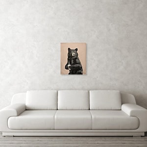 May include: A black bear with a white patch on its chest stands on a light brown background.