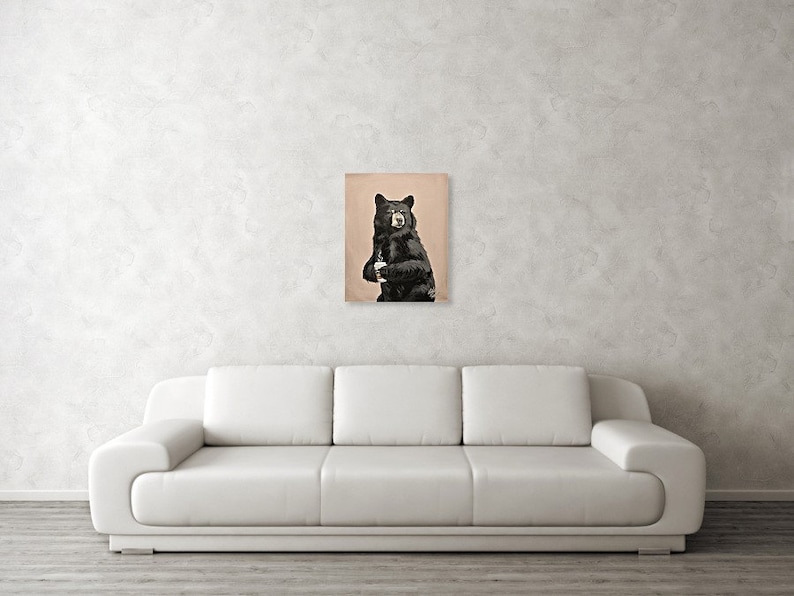 May include: A black bear with a white patch on its chest stands on a light brown background.